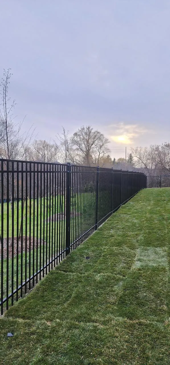 Black aluminum ornamental fence running along a landscaped yard