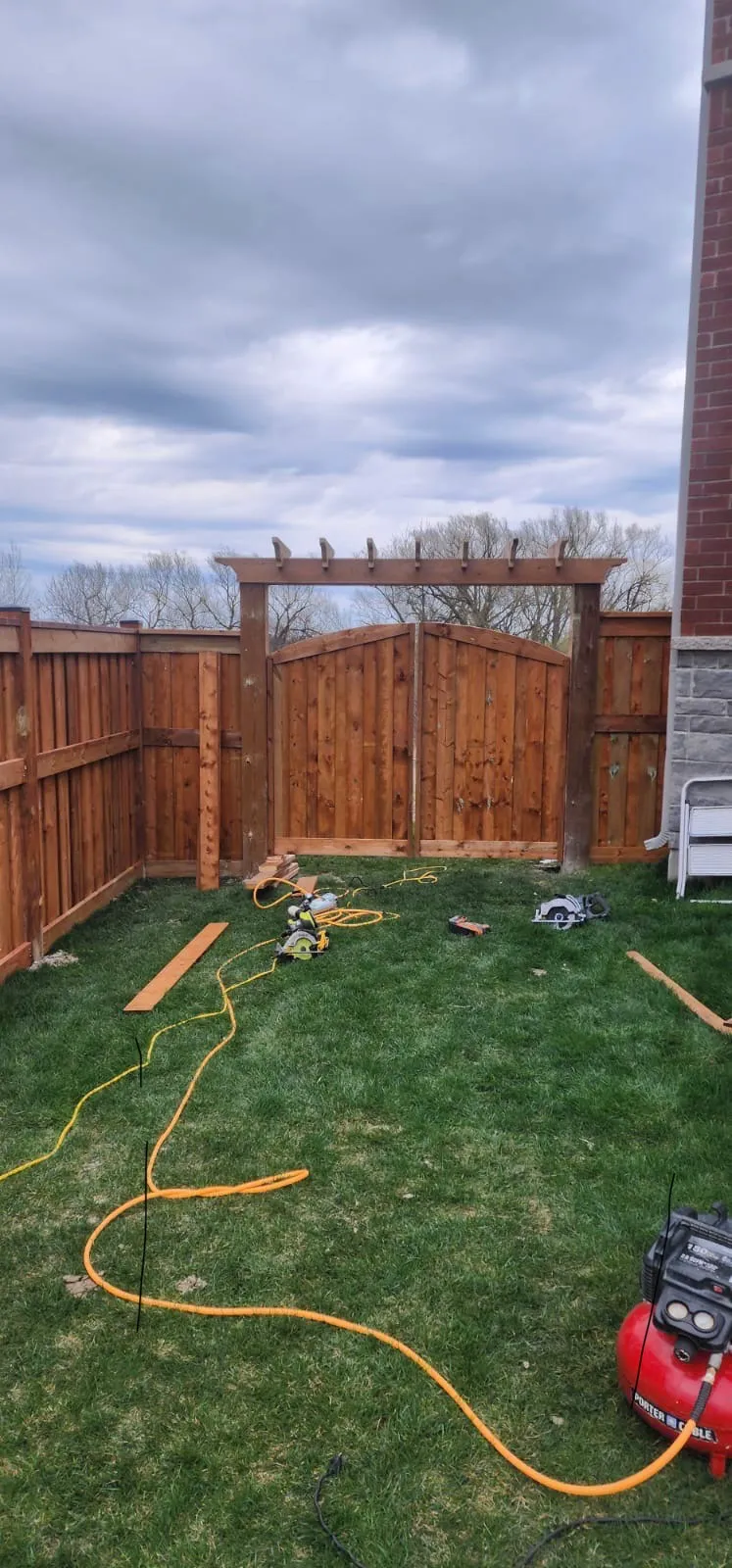 Cedar fence with a pergola-style arbor gate under construction