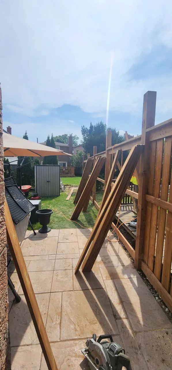 Wood privacy fence installation in progress beside a patio