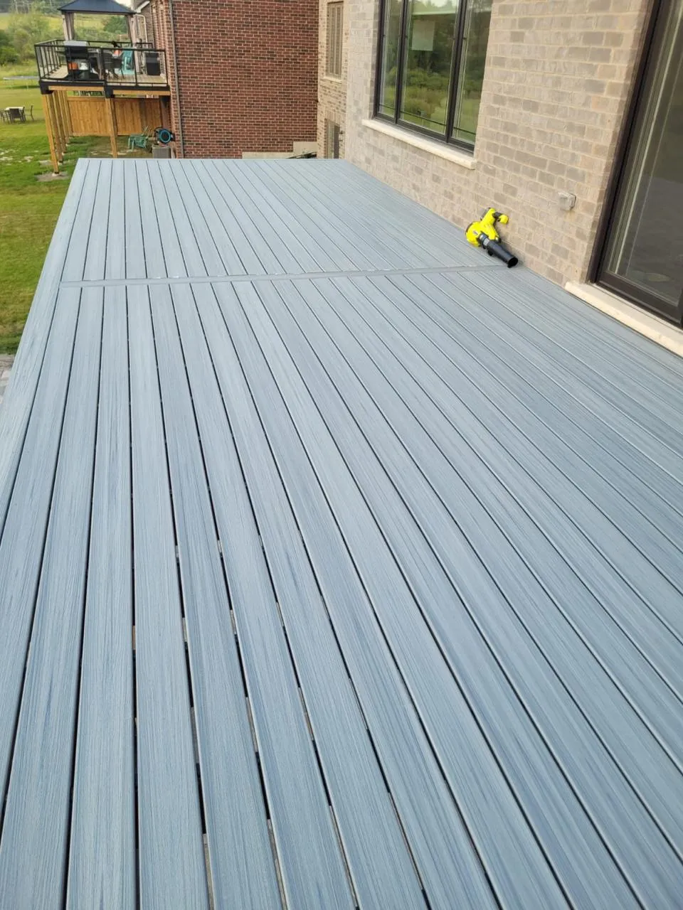 Grey composite deck along the back of a brick home
