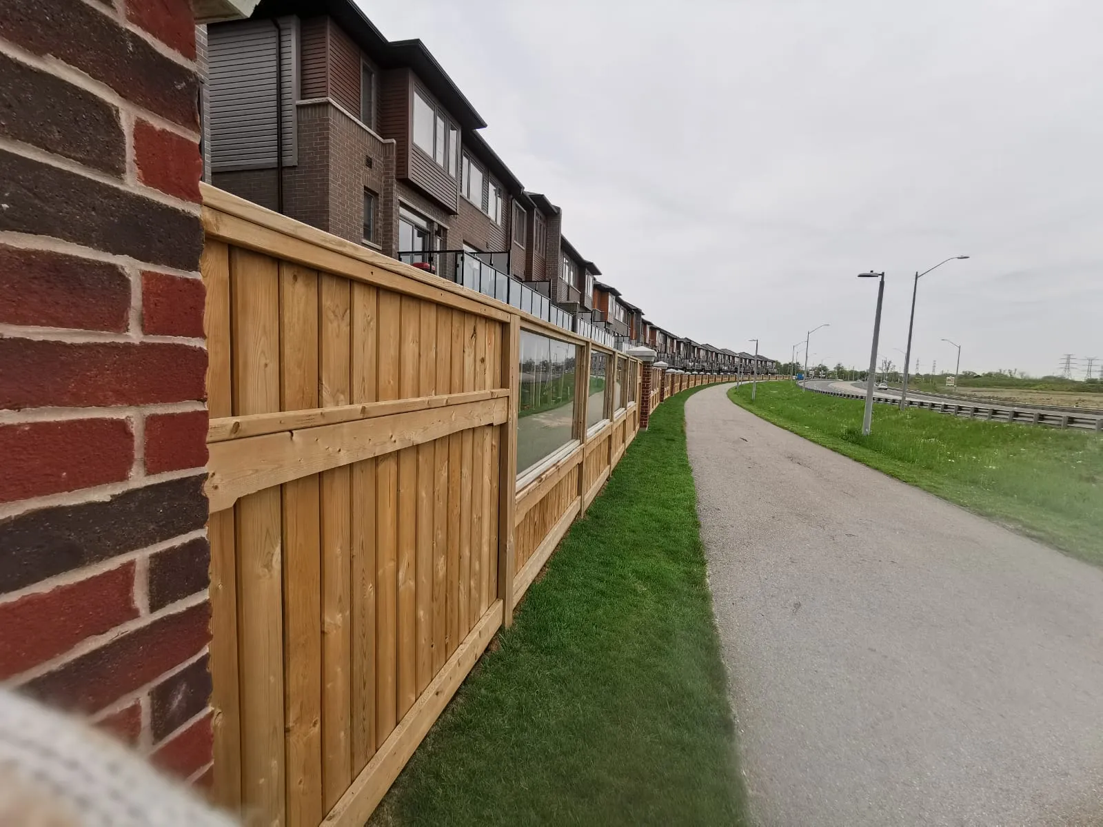 Cedar fence with glass railing panels along a pathway
